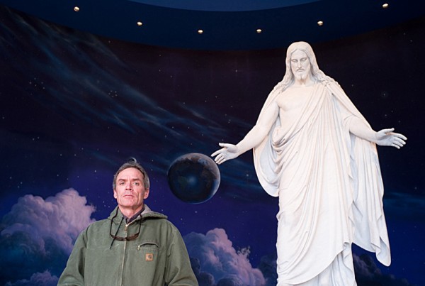 Scott Carrier below a religious statue, photo by Julian Cardona