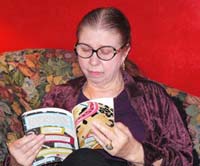 Lee Grue reading a poem on her couch