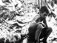 Boy sits among bombed buildings, photo by Julien Bryan