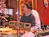 Photo, by Eleonora Alberto, of Cyro Baptista, surrounded by percussion instruments